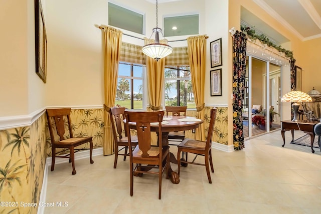 dining room with light tile patterned floors, crown molding, and a wainscoted wall