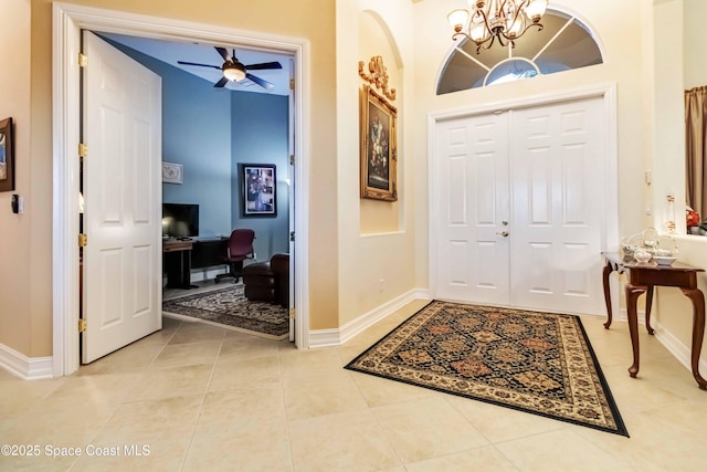 entrance foyer with ceiling fan with notable chandelier, light tile patterned floors, and baseboards