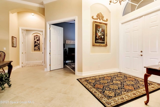 entryway featuring arched walkways, light tile patterned floors, and baseboards