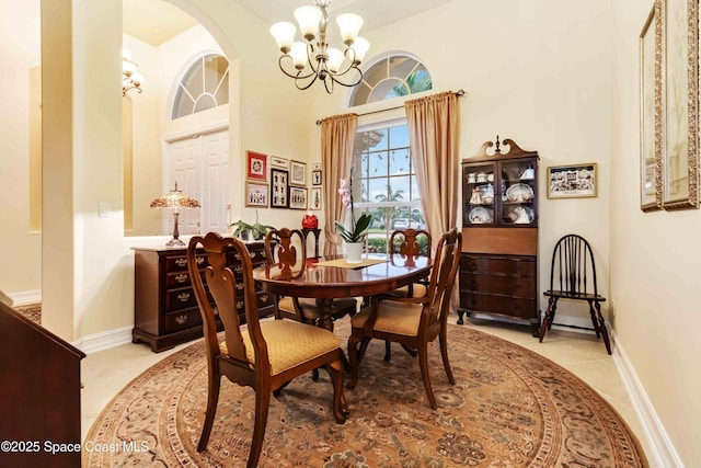 dining space with arched walkways, a notable chandelier, baseboards, and light tile patterned flooring