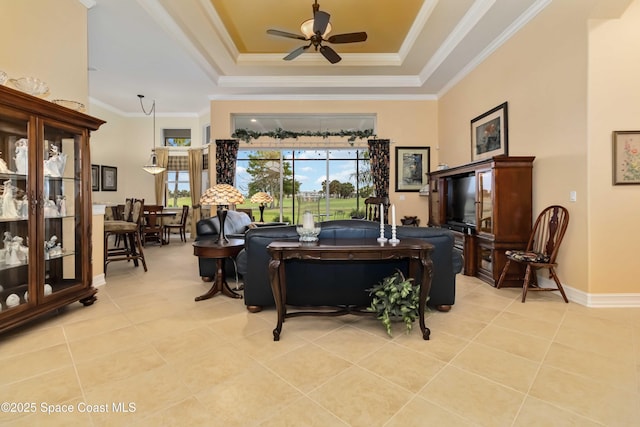 living room with a raised ceiling, crown molding, light tile patterned floors, and a ceiling fan