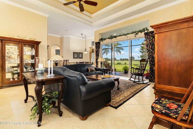living room featuring crown molding, light tile patterned floors, a ceiling fan, and a raised ceiling
