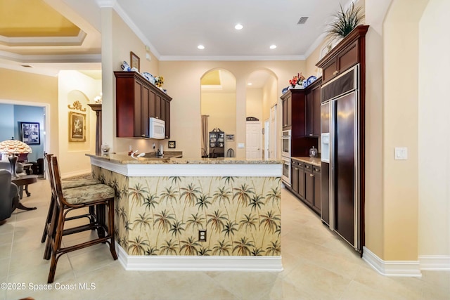 kitchen featuring white microwave, visible vents, light tile patterned flooring, paneled built in fridge, and oven