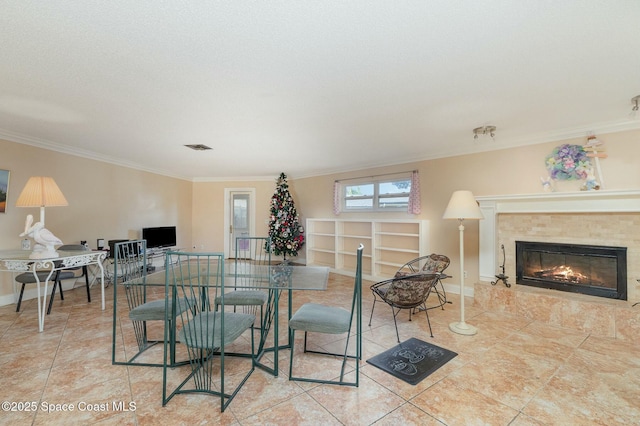 dining space with a tiled fireplace, tile patterned floors, visible vents, baseboards, and ornamental molding