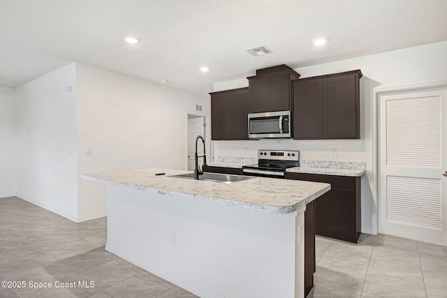 1217 Casey Ave, Rockledge, FL 32955 - kitchen with appliances with stainless steel finishes, a kitchen island with sink, light countertops, dark brown cabinetry, and a textured ceiling
