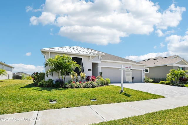 2257 Kamin Dr, Melbourne, FL 32940 - view of front of property featuring a garage, stucco siding, decorative driveway, and a front lawn