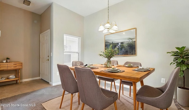 dining space with a chandelier, tile patterned flooring, a high ceiling, and baseboards
