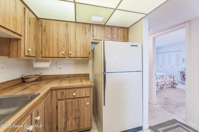 kitchen featuring butcher block countertops, a sink, freestanding refrigerator, and light tile patterned floors