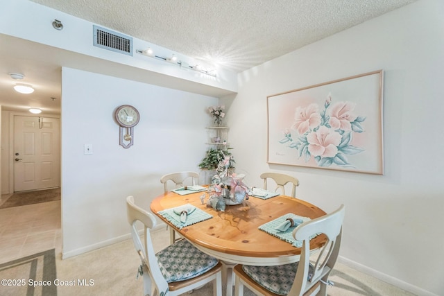 dining area with light carpet, visible vents, a textured ceiling, and baseboards