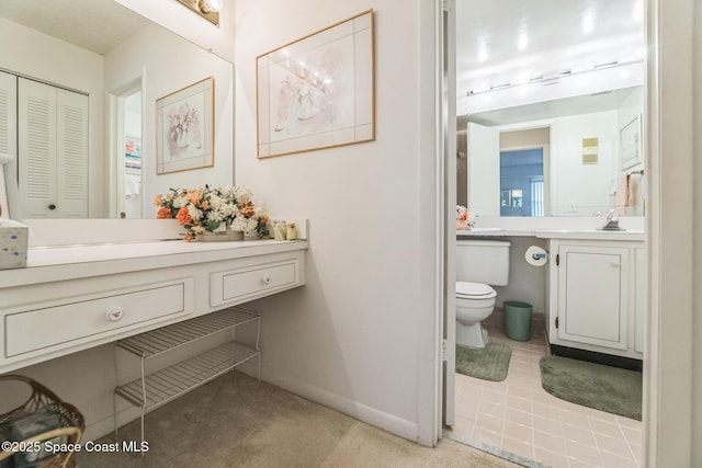 bathroom featuring a closet, vanity, toilet, tile patterned floors, and baseboards