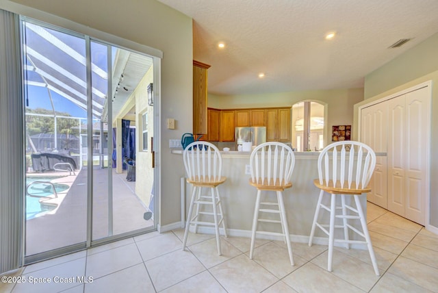 1772 Windbrook Dr SE, Palm Bay, FL 32909 - kitchen featuring visible vents, brown cabinetry, freestanding refrigerator, and a healthy amount of sunlight