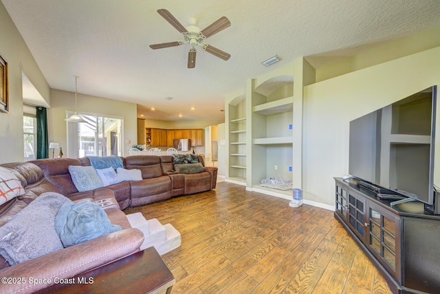 1772 Windbrook Dr SE, Palm Bay, FL 32909 - living room featuring a ceiling fan, wood finished floors, built in features, baseboards, and visible vents