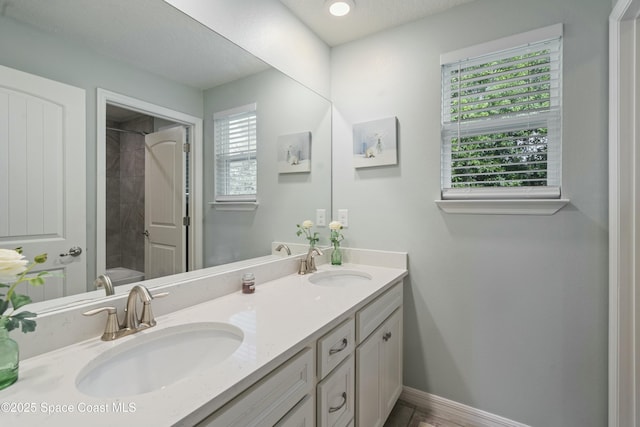 full bath with double vanity, baseboards, a sink, and a washtub