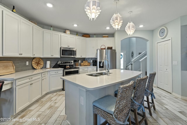 kitchen with a sink, appliances with stainless steel finishes, arched walkways, and wood tiled floor