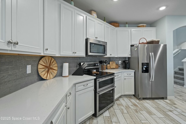 kitchen featuring backsplash, light countertops, white cabinetry, and stainless steel appliances