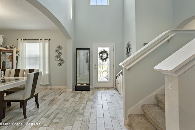 entrance foyer with arched walkways, plenty of natural light, and stairs