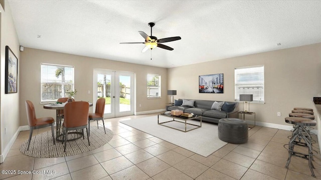 living room with french doors, baseboards, a ceiling fan, and a textured ceiling