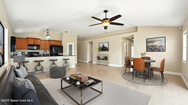 living area featuring baseboards, ceiling fan, vaulted ceiling, and light tile patterned flooring