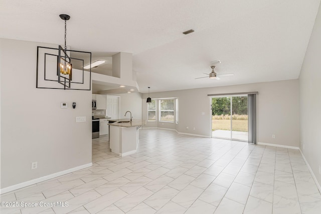 unfurnished living room with ceiling fan with notable chandelier, baseboards, a sink, and lofted ceiling