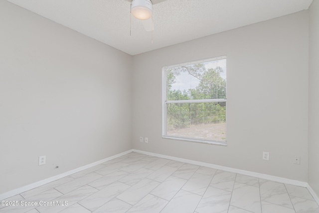 empty room featuring marble finish floor, baseboards, a textured ceiling, and ceiling fan