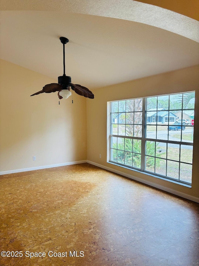 unfurnished room featuring baseboards, ceiling fan, and a wealth of natural light