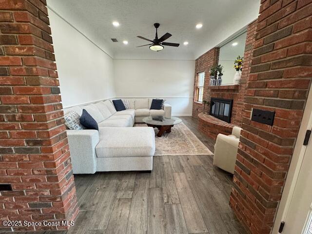 572 Lake Ashley Cir, Melbourne, FL 32904 - living room featuring dark wood-style flooring, a fireplace, ceiling fan, brick wall, and recessed lighting