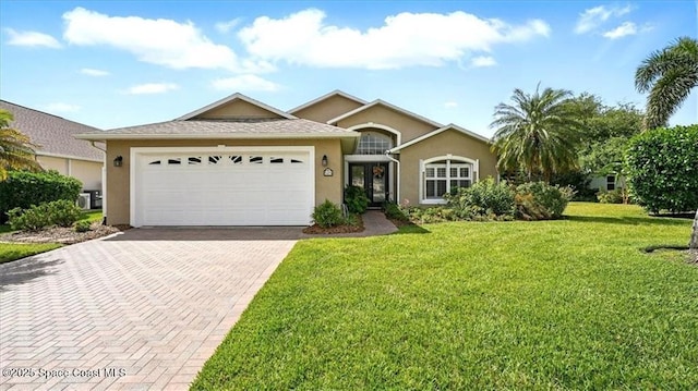 ranch-style home with a front yard, decorative driveway, stucco siding, and an attached garage
