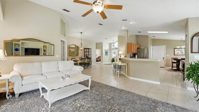 living area with lofted ceiling, baseboards, light tile patterned floors, ceiling fan with notable chandelier, and visible vents