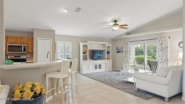 living area featuring plenty of natural light, lofted ceiling, light tile patterned flooring, and ceiling fan