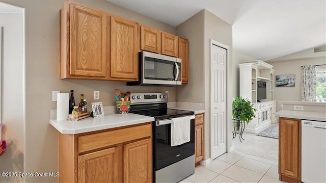 kitchen with vaulted ceiling, light countertops, appliances with stainless steel finishes, and light tile patterned floors