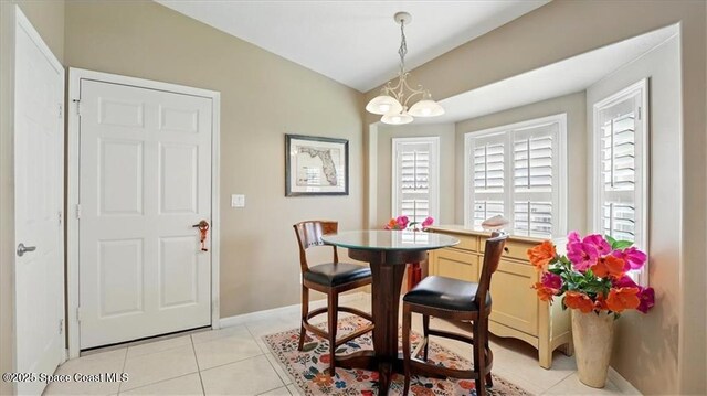dining space featuring baseboards, vaulted ceiling, an inviting chandelier, and light tile patterned floors