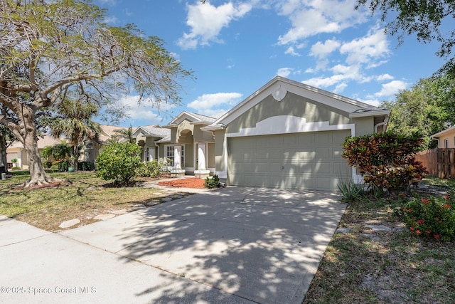 single story home with a garage, stucco siding, concrete driveway, and fence