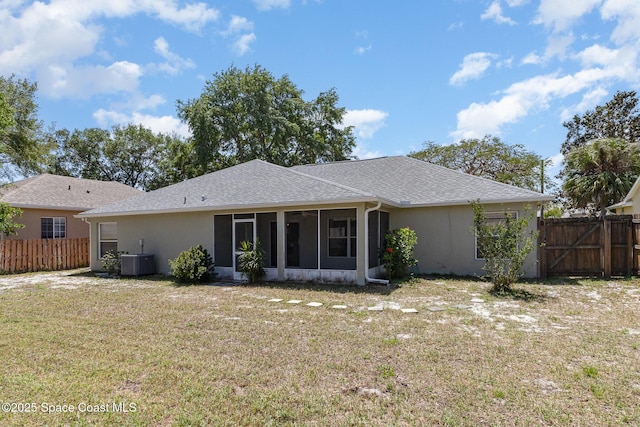 rear view of property featuring fence, a lawn, a sunroom, and stucco siding