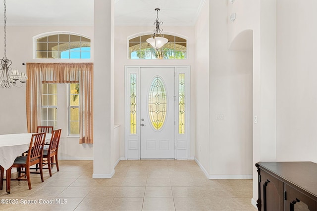 foyer entrance with a chandelier, ornamental molding, and baseboards