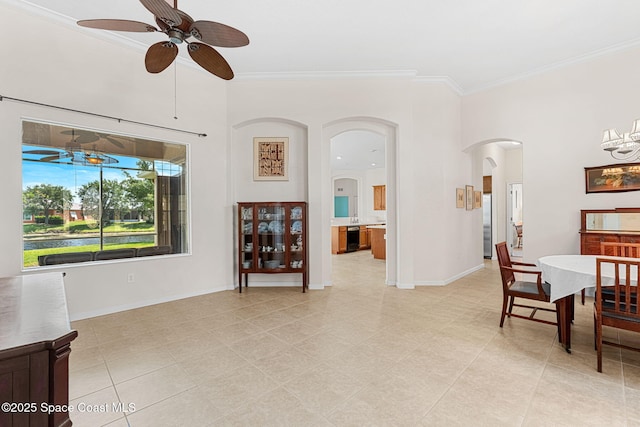 dining space with baseboards, ornamental molding, ceiling fan with notable chandelier, and arched walkways