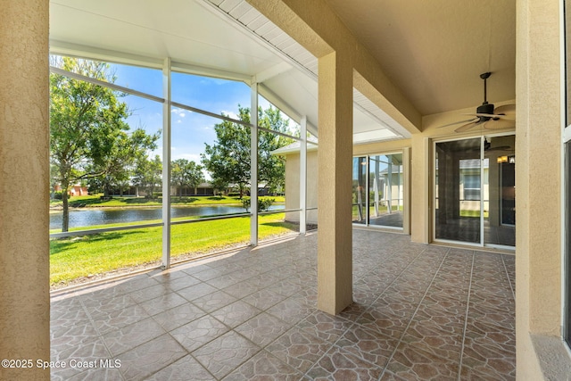 unfurnished sunroom featuring ceiling fan and a water view