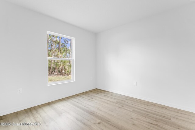 spare room with baseboards and light wood-style floors