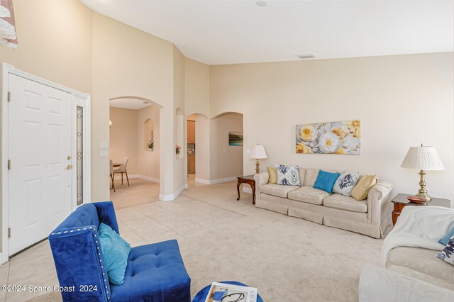 2842 Galindo Cir, Melbourne, FL 32940 - living area with light tile patterned floors, baseboards, a towering ceiling, arched walkways, and light carpet