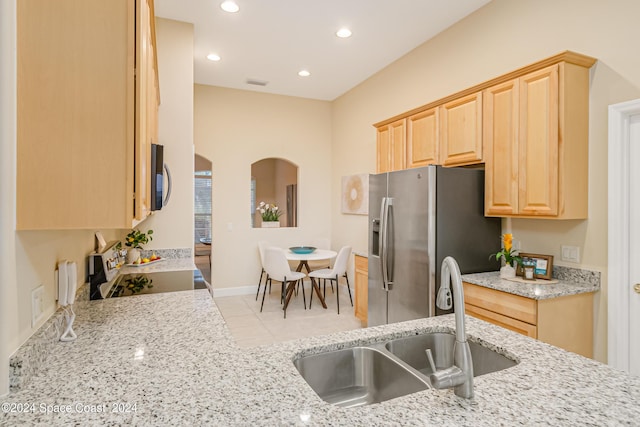 2842 Galindo Cir, Melbourne, FL 32940 - kitchen with light stone counters, a sink, appliances with stainless steel finishes, light brown cabinetry, and arched walkways