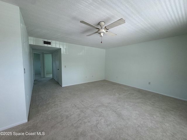 spare room with carpet, a textured ceiling, visible vents, and a ceiling fan
