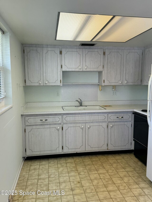 kitchen featuring light countertops, a sink, range with electric stovetop, and freestanding refrigerator