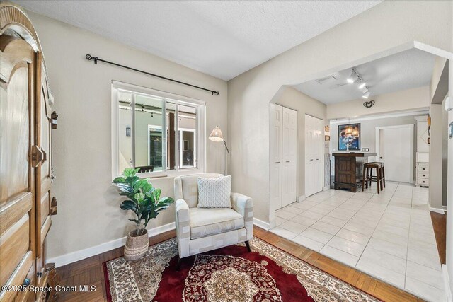 sitting room with baseboards, arched walkways, and wood finished floors