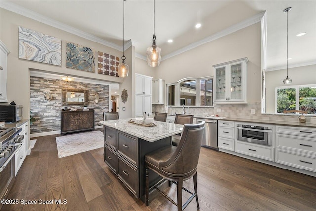 kitchen with dark wood-style floors, appliances with stainless steel finishes, glass insert cabinets, and a kitchen breakfast bar