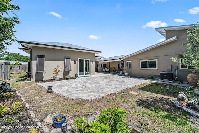 back of house with central air condition unit, stucco siding, a patio area, metal roof, and fence