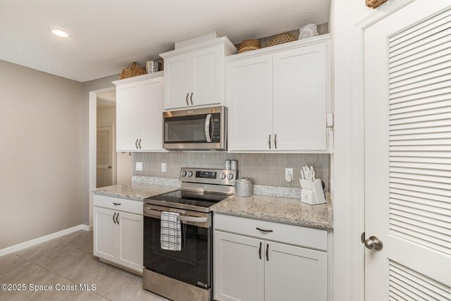6575 Topaz Dr, Grant, FL 32949 - kitchen with light tile patterned floors, white cabinets, baseboards, stainless steel appliances, and backsplash