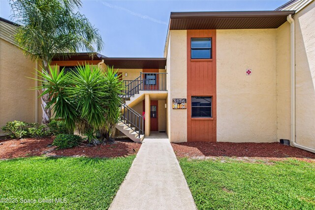 2334 Golf Lake Cir Unit 424, Melbourne, FL 32935 - doorway to property featuring stucco siding and a yard