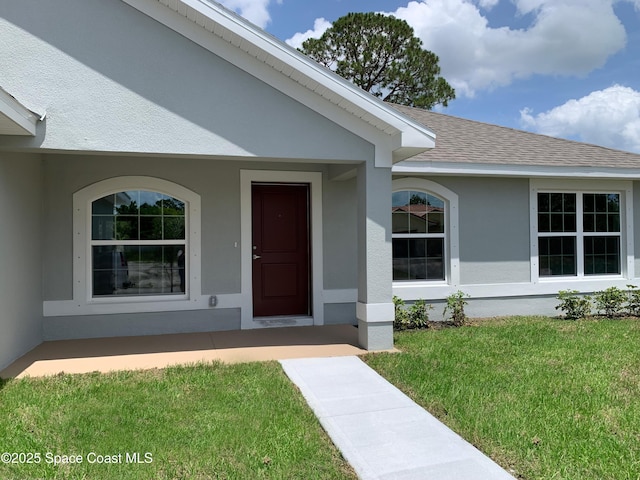 1099 Hanson Ave SW, Palm Bay, FL 32908 - doorway to property featuring a lawn, stucco siding, and a shingled roof