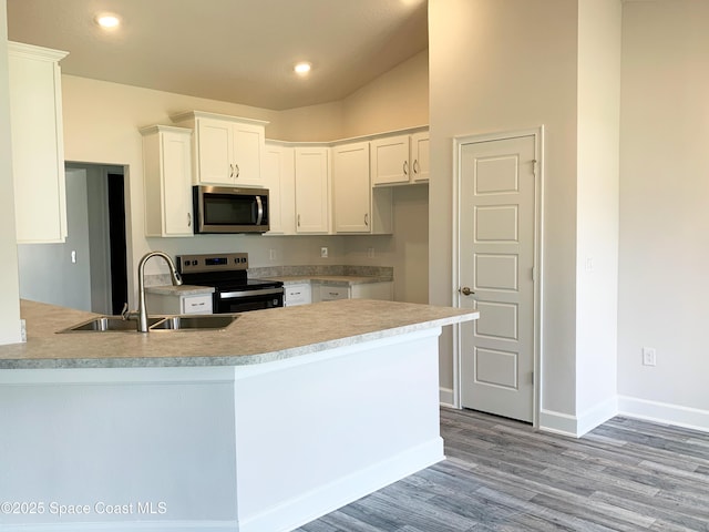 1099 Hanson Ave SW, Palm Bay, FL 32908 - kitchen featuring appliances with stainless steel finishes, light wood-style flooring, a peninsula, white cabinetry, and light countertops