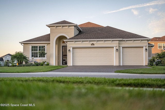 mediterranean / spanish-style house featuring a yard, an attached garage, stucco siding, and driveway