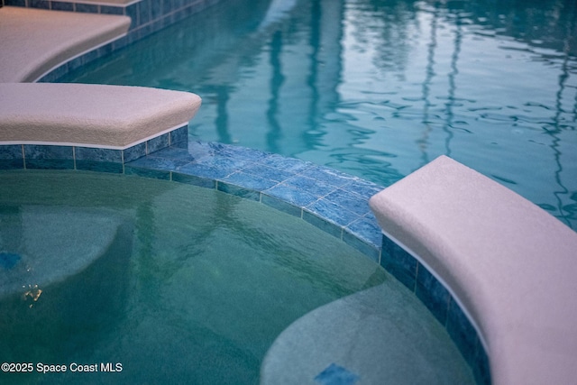 view of pool with a pool with connected hot tub